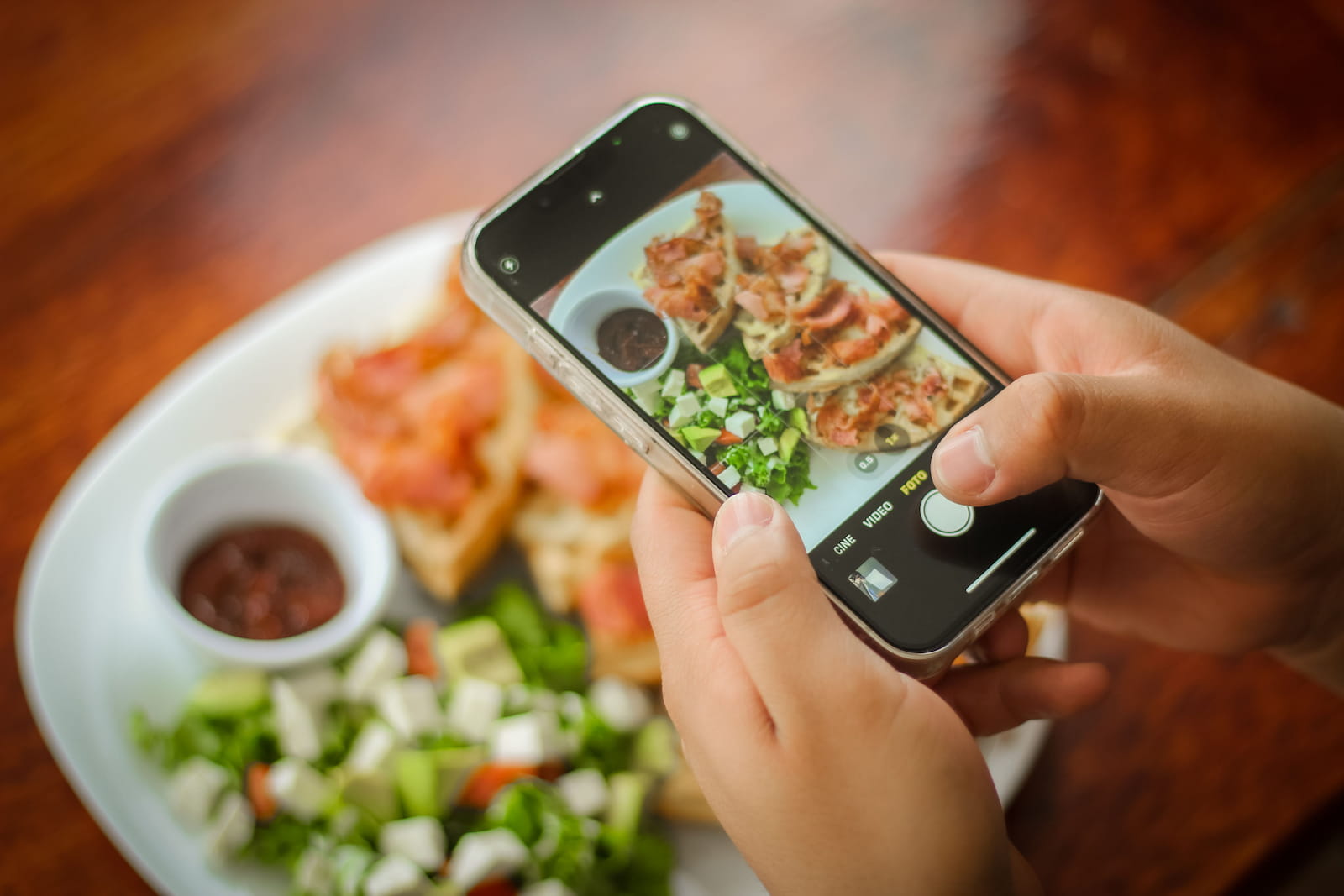 Une personne photographie son assiette avec son téléphone au restaurant